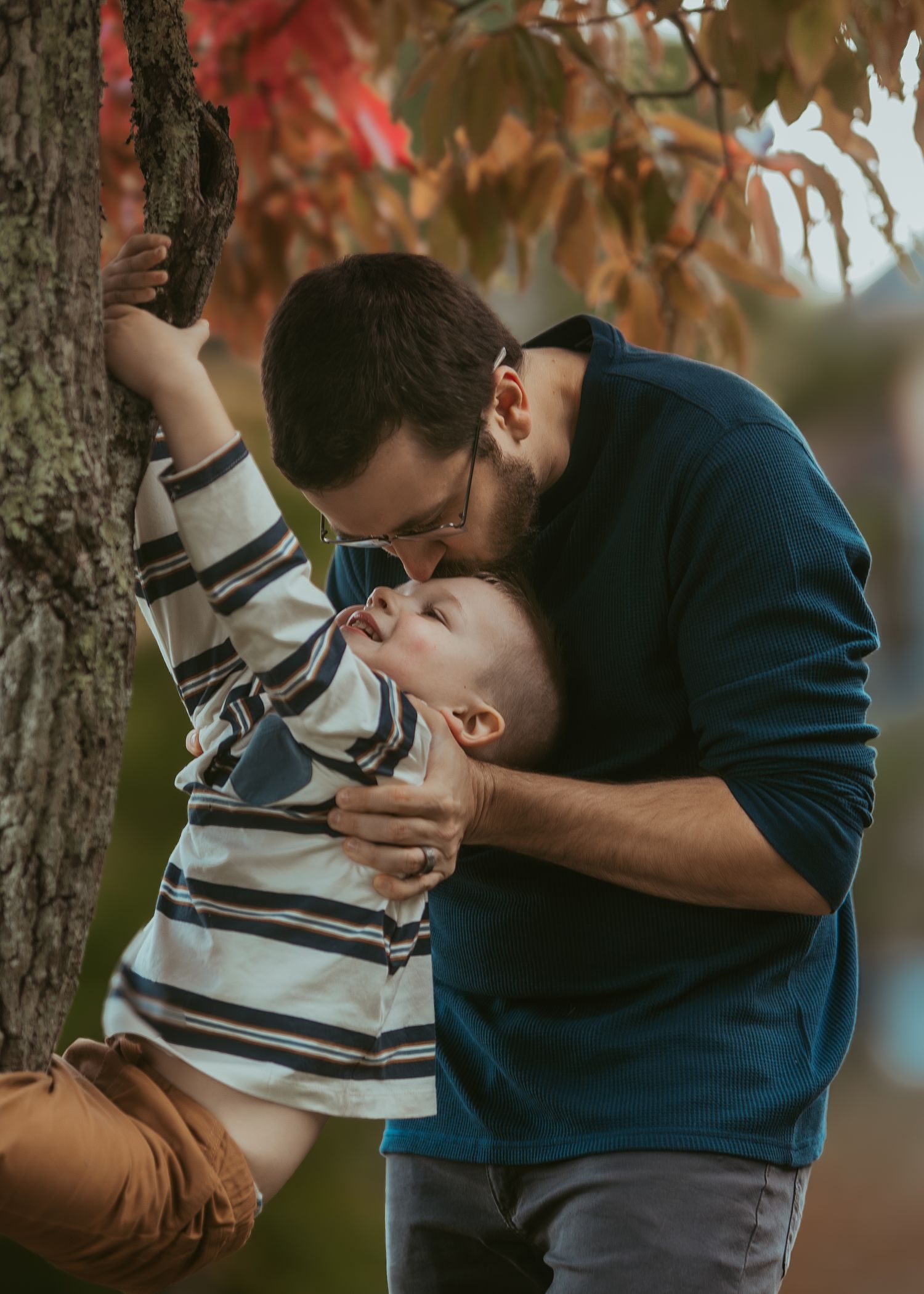 A series of playful moments between a parent and child in striped shirt under autumn trees at sunset.