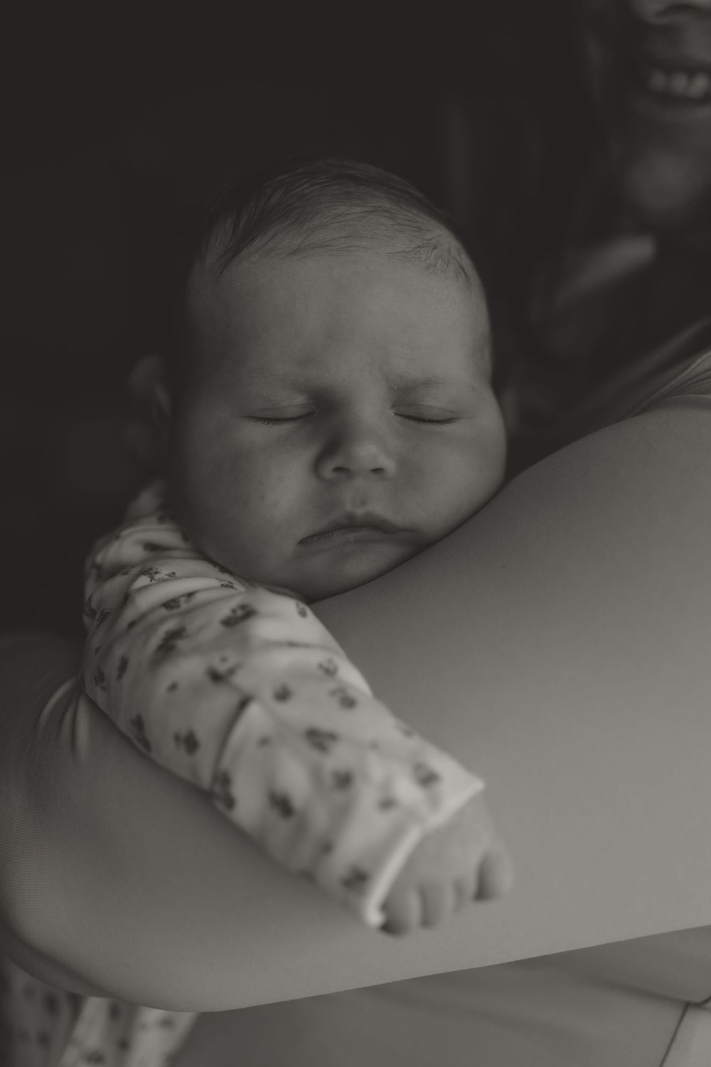 Peaceful sleeping newborn rests in her mothers arms.