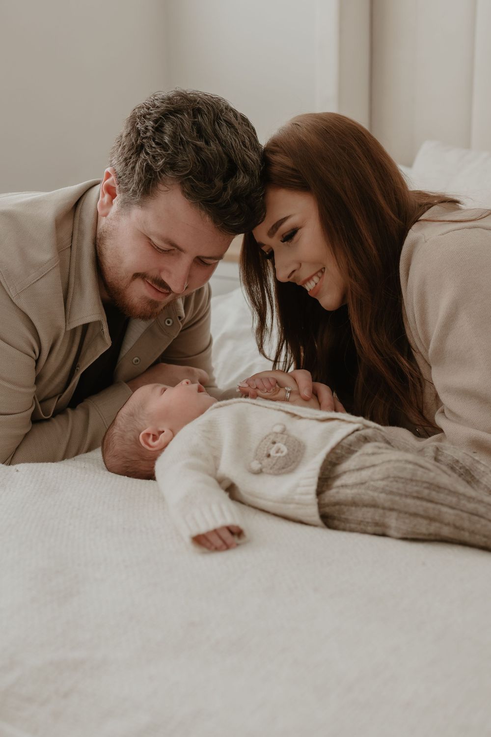Parents lovingly gaze at their sleeping newborn baby in a tender bedside moment.