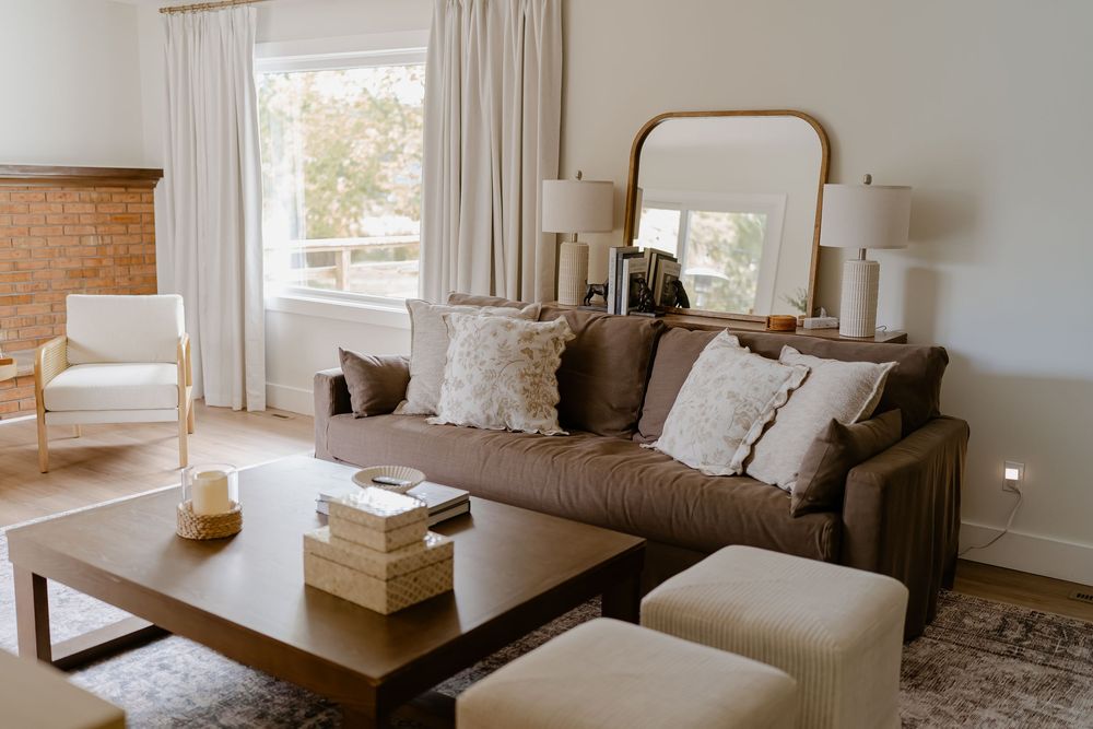 Modern minimalist living room interior with white walls, wooden accents, and natural light from windows.