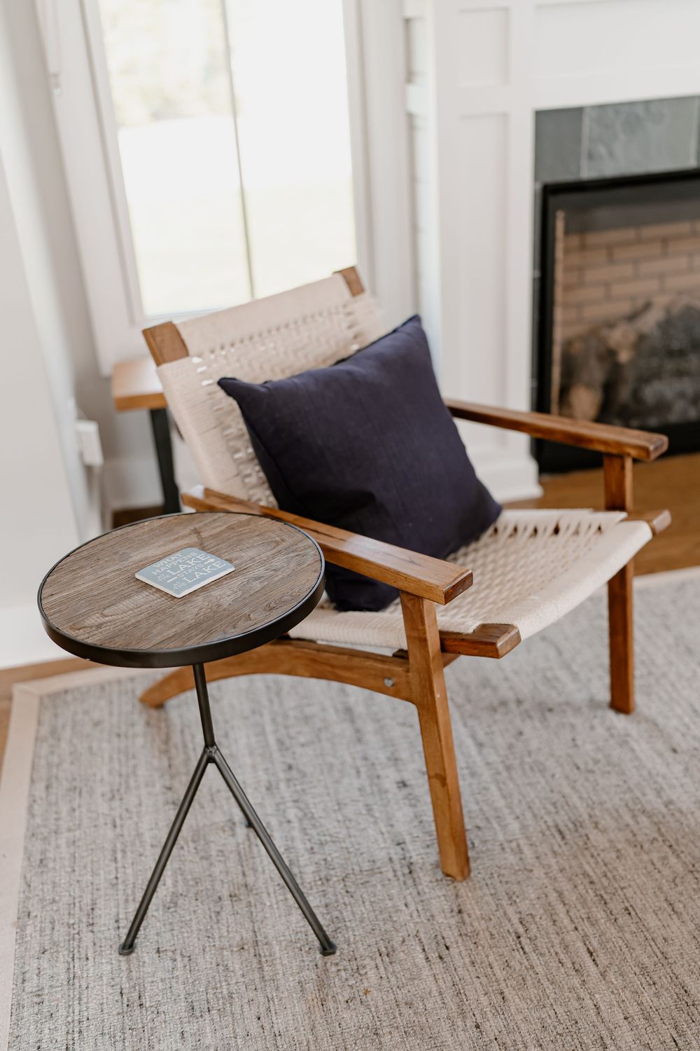 Modern wooden accent chair with navy cushion and metal base displayed on textured gray rug in bright interior space.