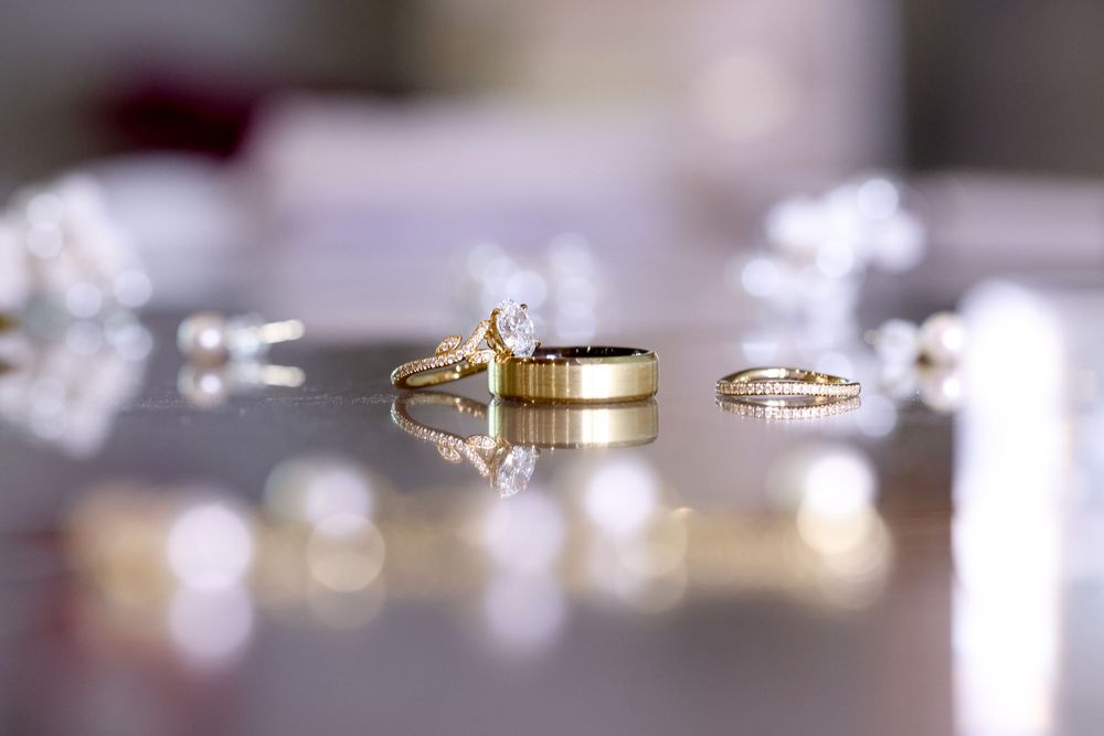 Macro shot of gold wedding rings on reflective surface with bokeh effect.