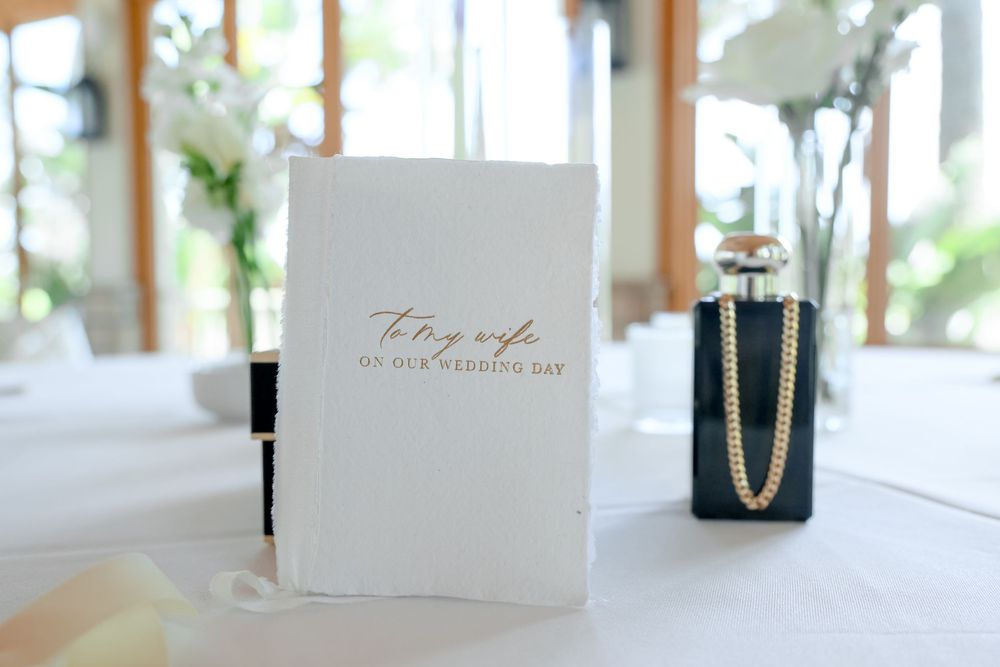 Elegant wedding decor details including place cards, flowers and table settings in a bright sunlit room.