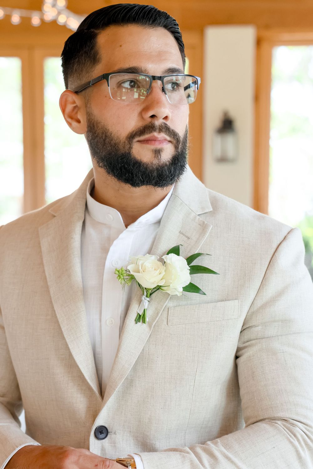 Groomsmen wearing light beige suits with white boutonnieres lined up for wedding photo.