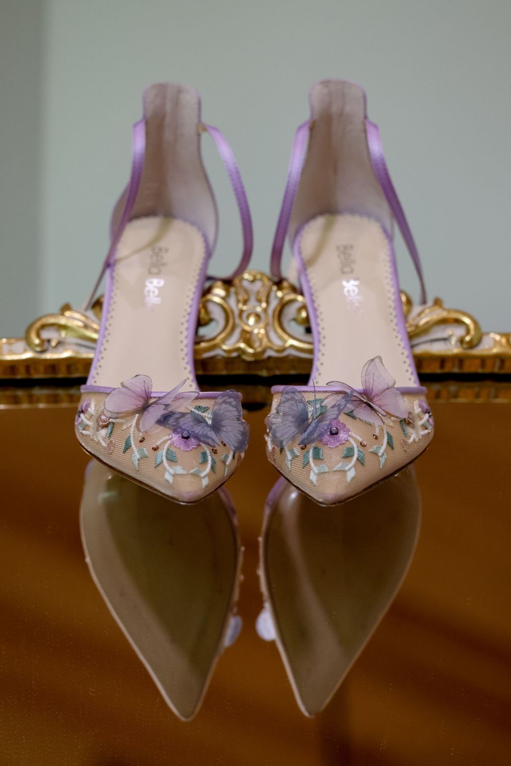 Elegant pink bridal shoes with crystal embellishments displayed on a reflective surface.