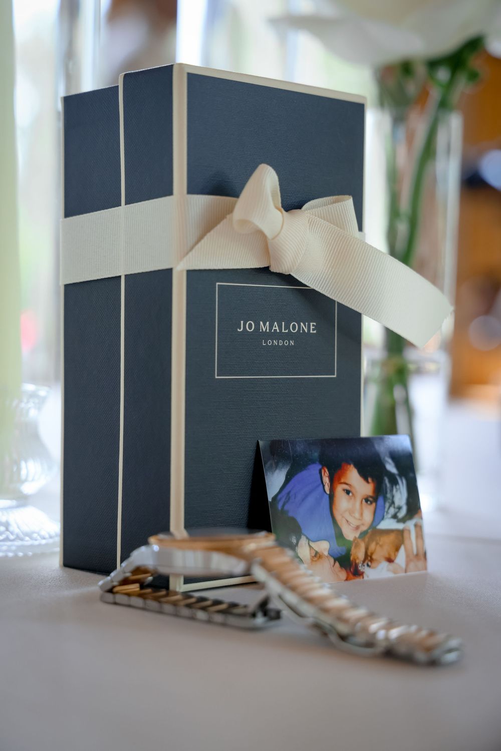 Row of elegant gray Jo Malone gift boxes with white bows displayed on table.