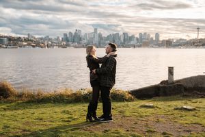 A scenic proposal moment silhouetted against the Seattle skyline and waterfront on a cloudy day.