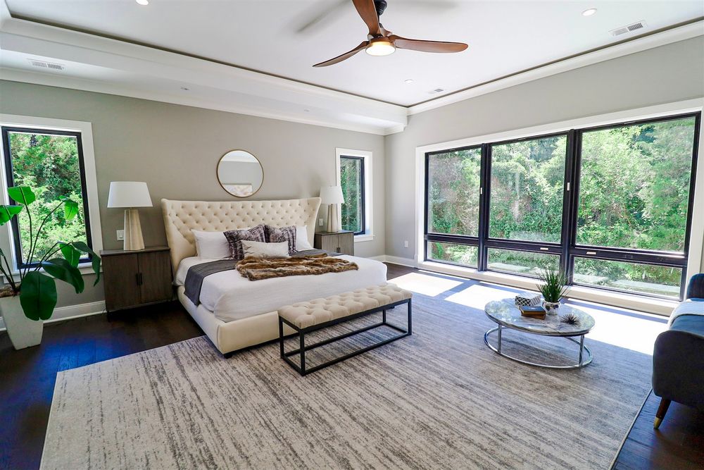 Bright modern bedroom with large windows, wood flooring, and natural light streaming in.
