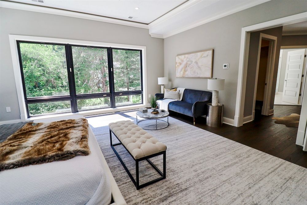 Contemporary bedroom featuring floor-to-ceiling windows with forest views and modern furnishings.