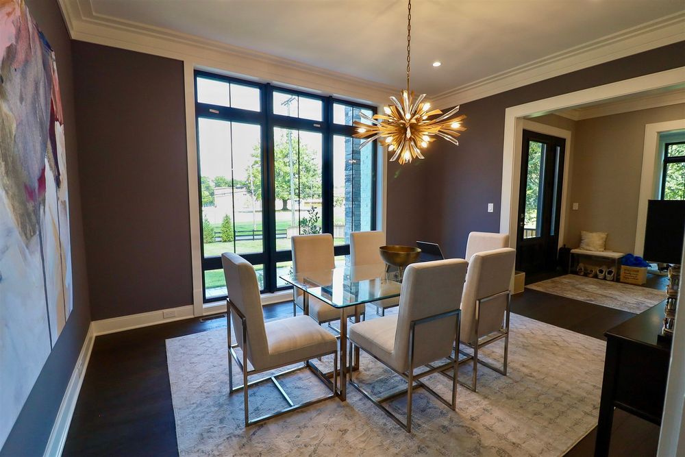 Elegant dining room with glass table, modern chandelier, and floor-to-ceiling windows.