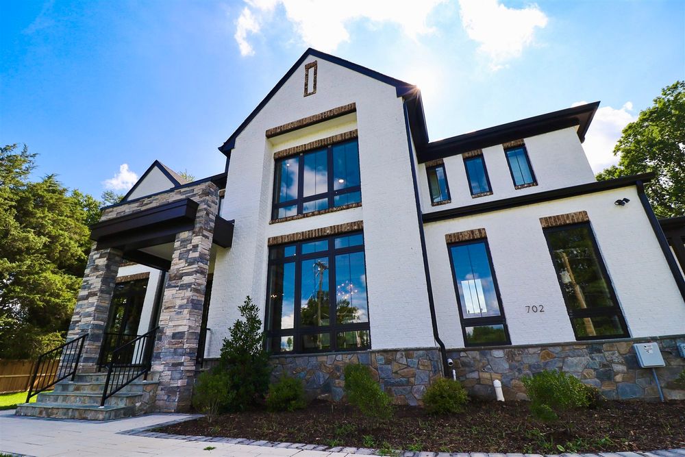 Modern farmhouse exterior featuring stone accents, black trim, and large architectural windows.