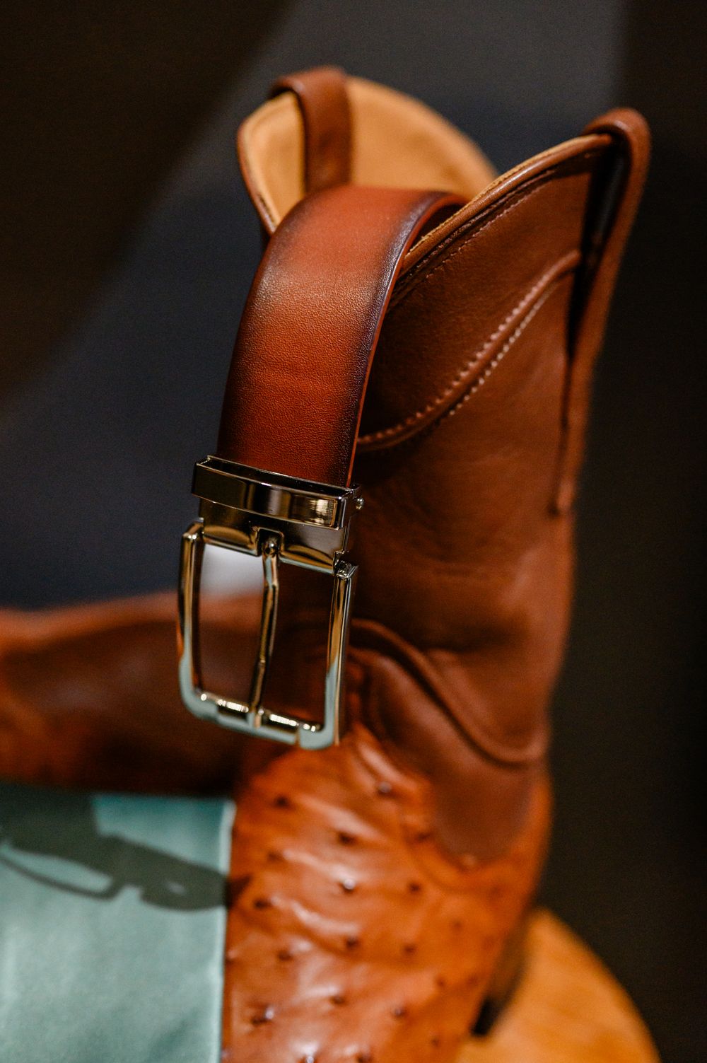 Close-up details of a brown leather dress shoe with decorative perforations and buckle fastening.