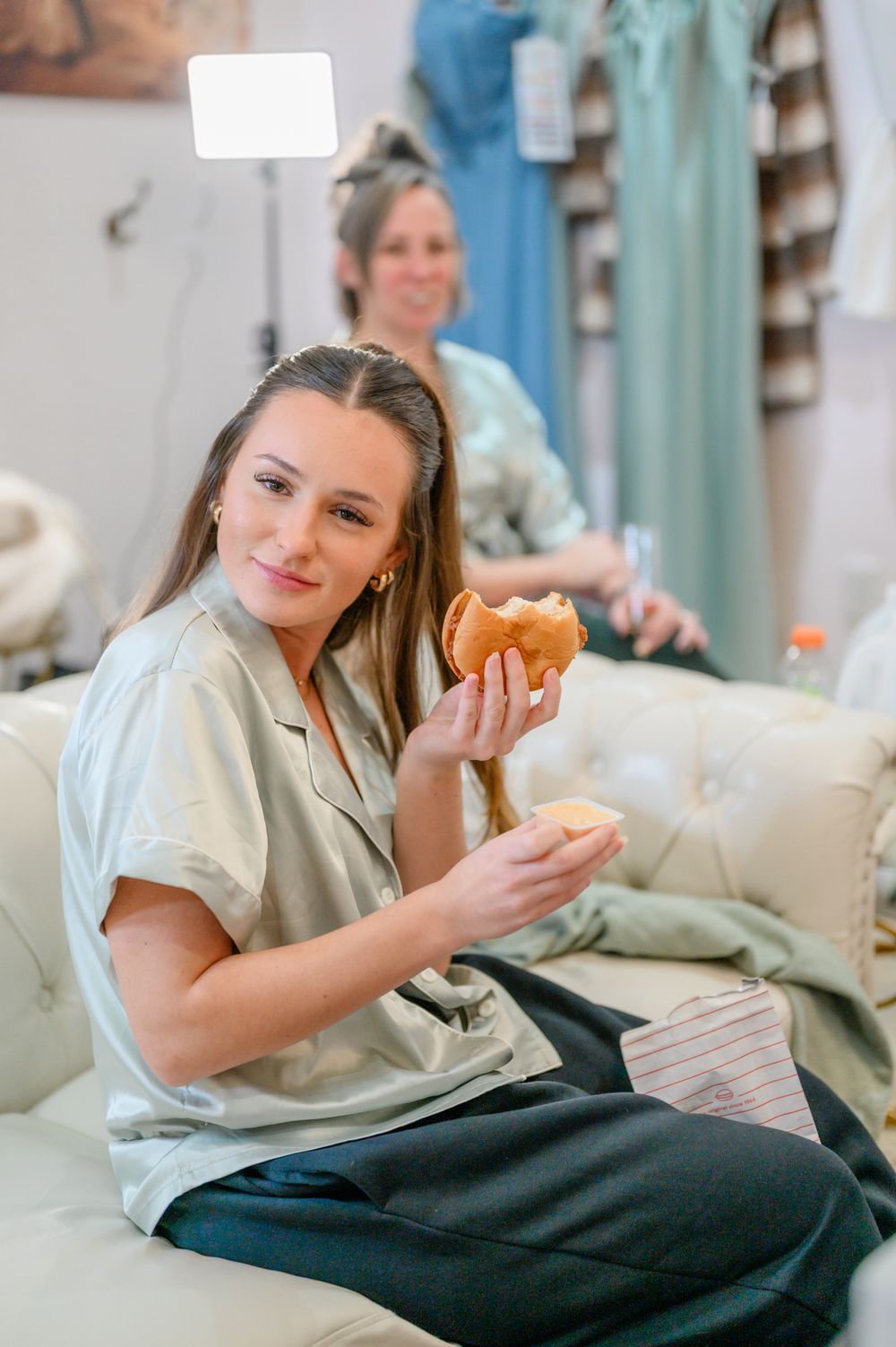 Someone relaxing on a couch in casual attire while eating a pastry.