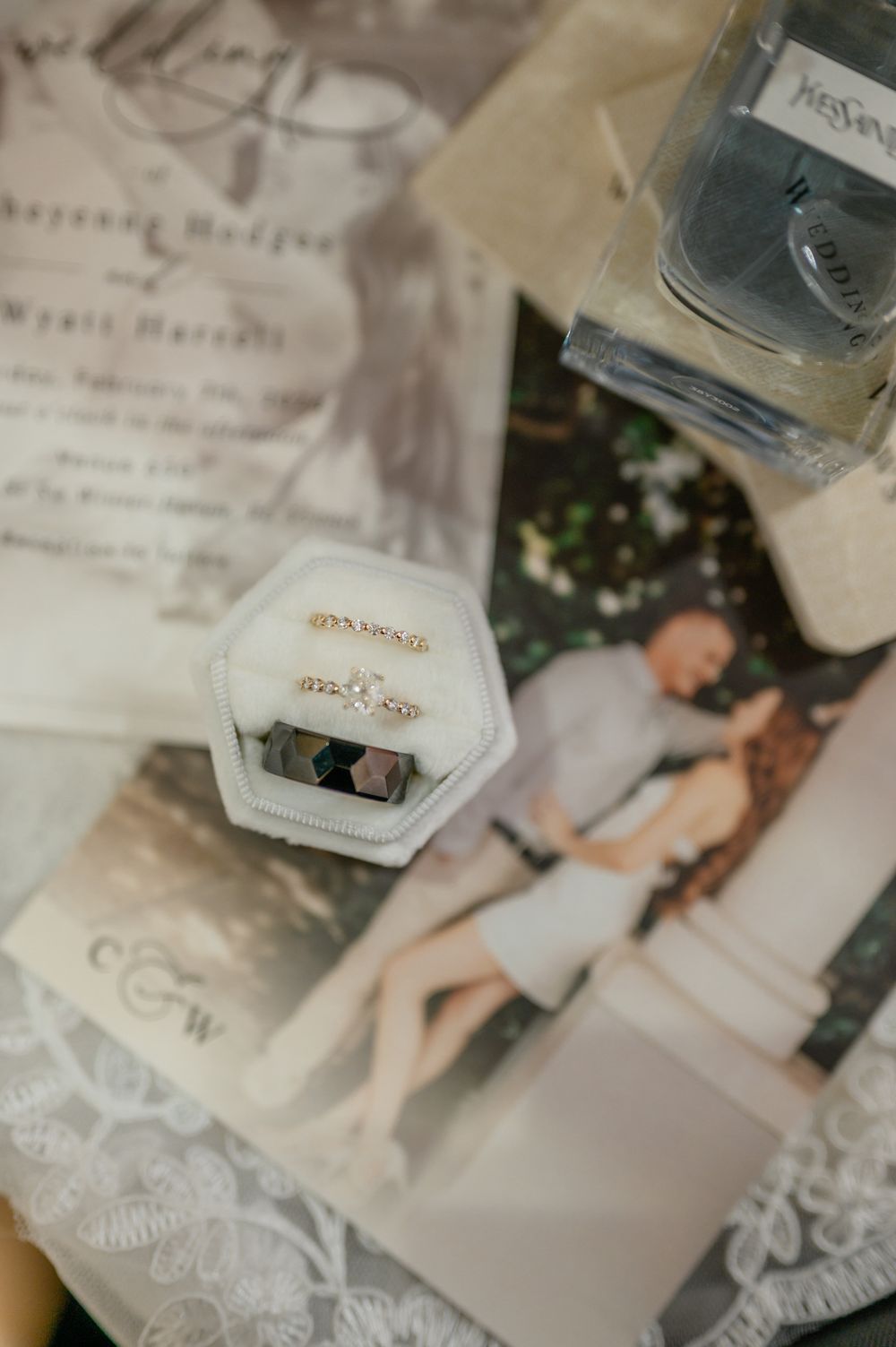 Wedding details including delicate lace and invitation cards arranged on a white surface.