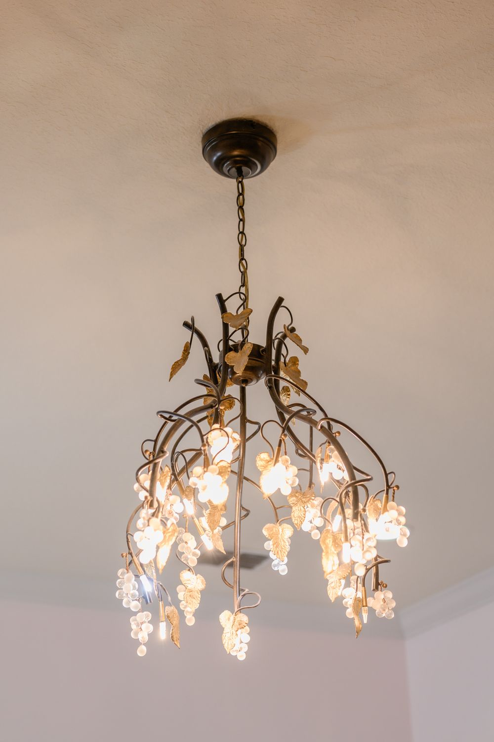 Elegant crystal chandelier with floral-shaped glass pendants illuminated against a neutral ceiling.