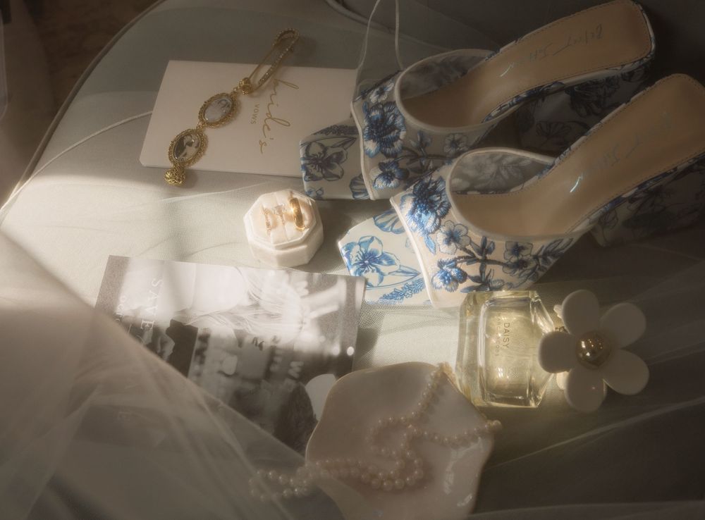 Wedding details including rings, invitations, and delicate decor items arranged on a light surface.