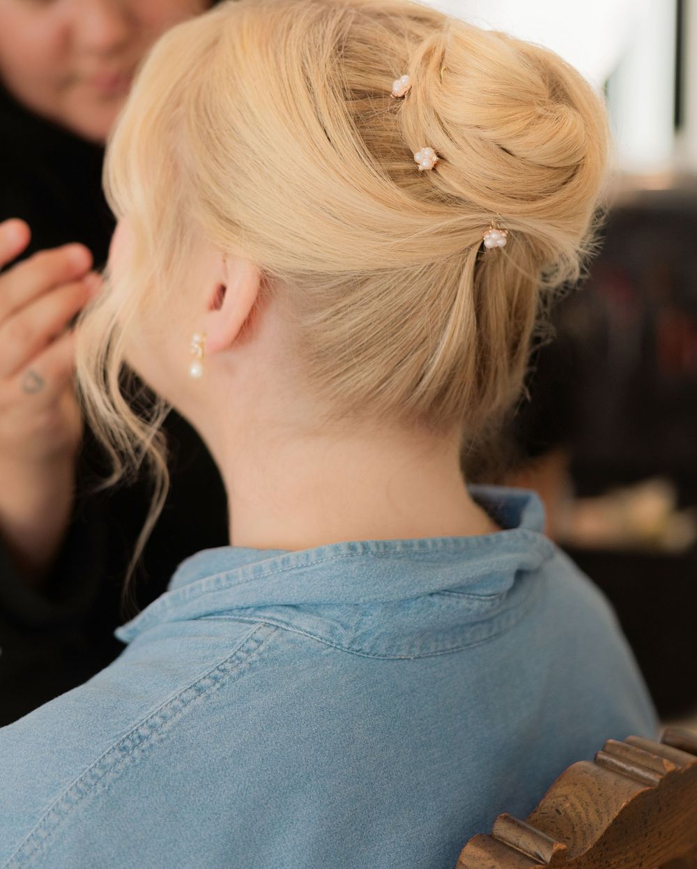 Back view of blonde hair being styled in an elegant updo at a salon.