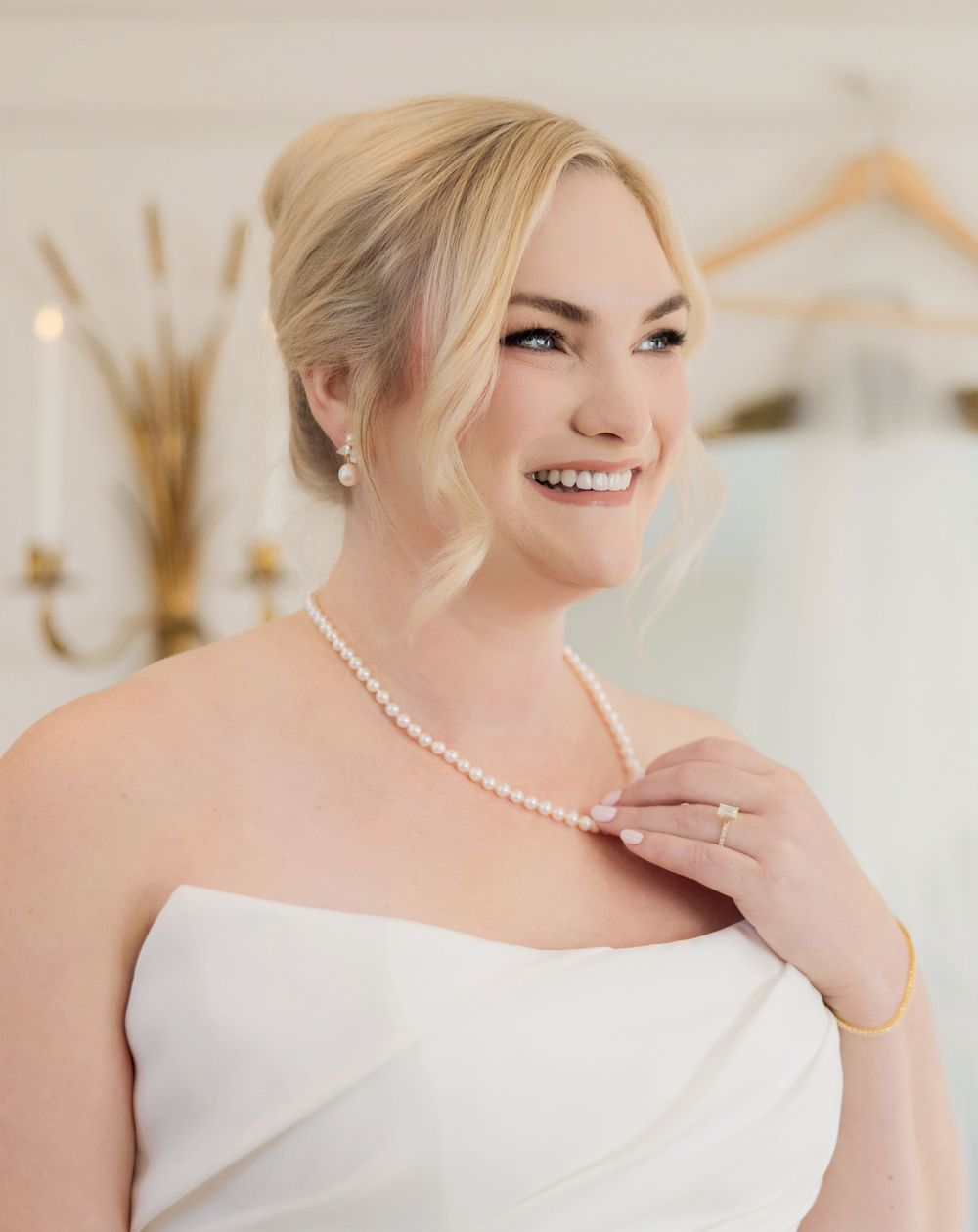 Elegant bridal portrait details featuring pearl necklace and off-shoulder white wedding dress.