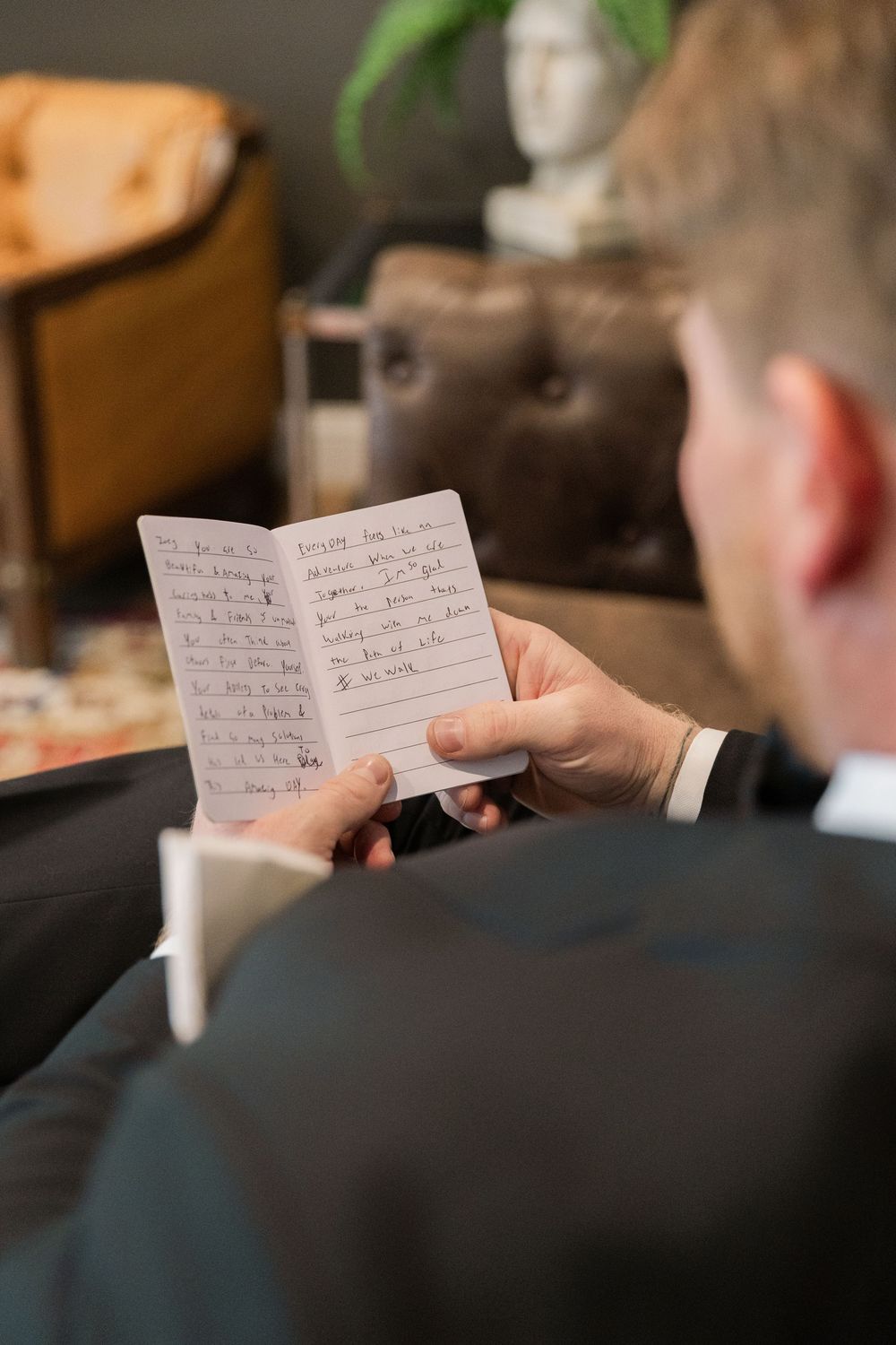 Two hands exchange handwritten wedding vows on small note cards during an intimate ceremony moment.