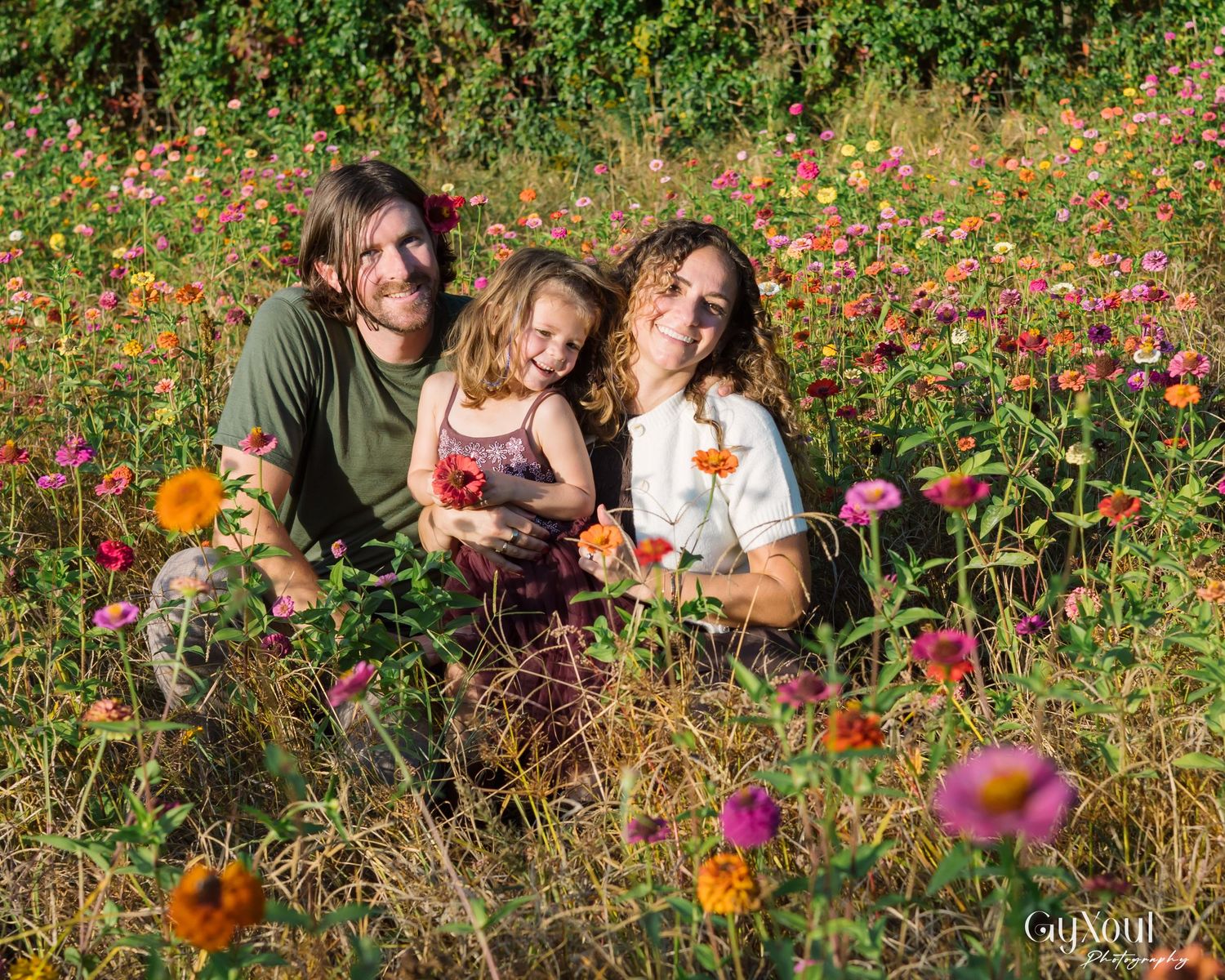 People sitting together in a vibrant wildflower meadow filled with colorful cosmos flowers on a sunny day.