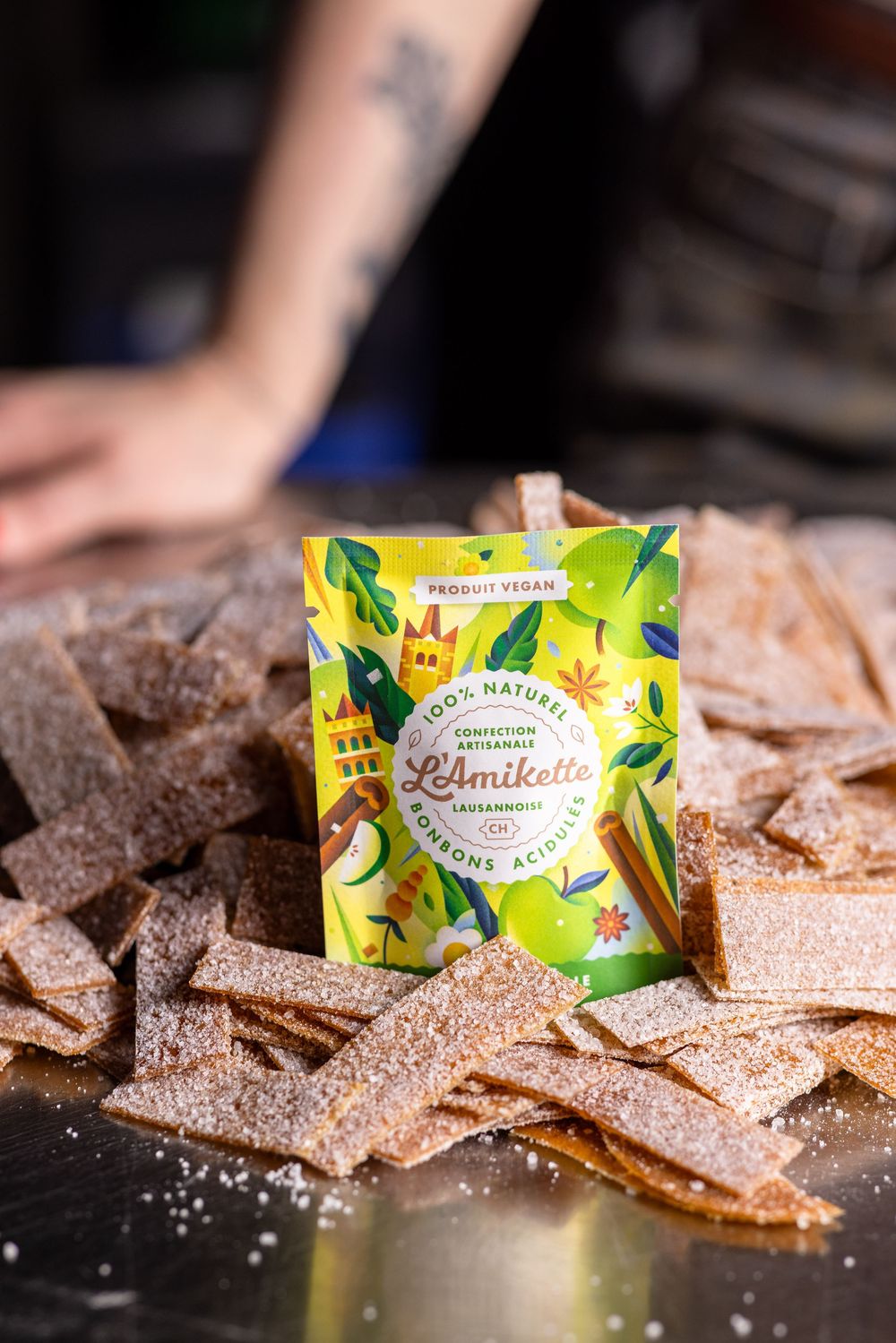 Crispy cinnamon sugar pita chips scattered on dark surface with colorful snack packaging in background.