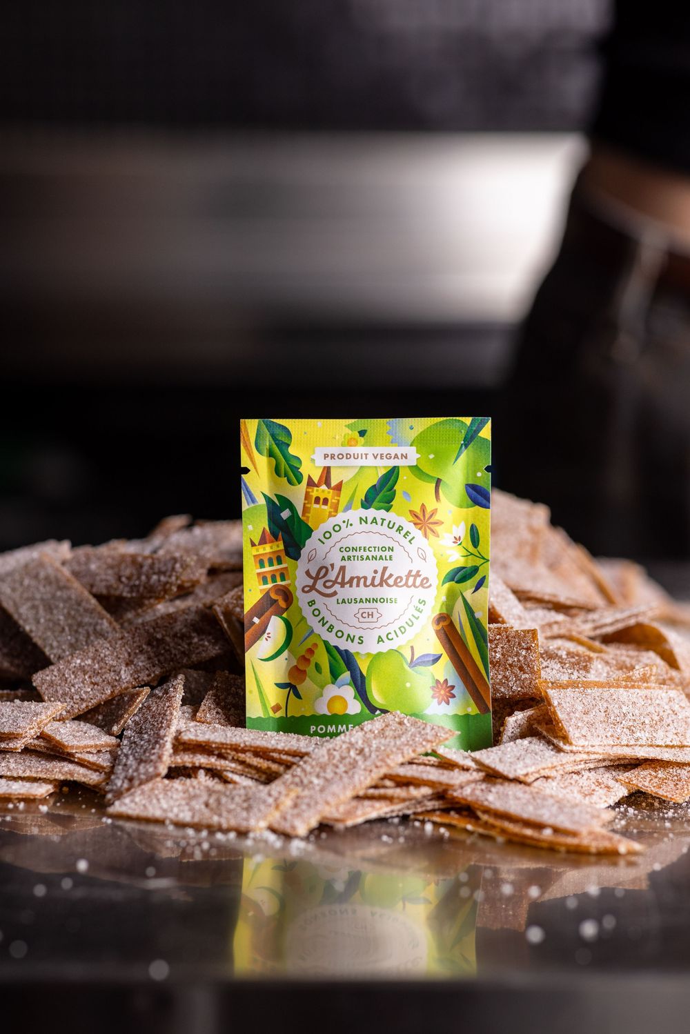 Artisanal crackers and colorful tea packaging displayed on dark surface with dramatic lighting.
