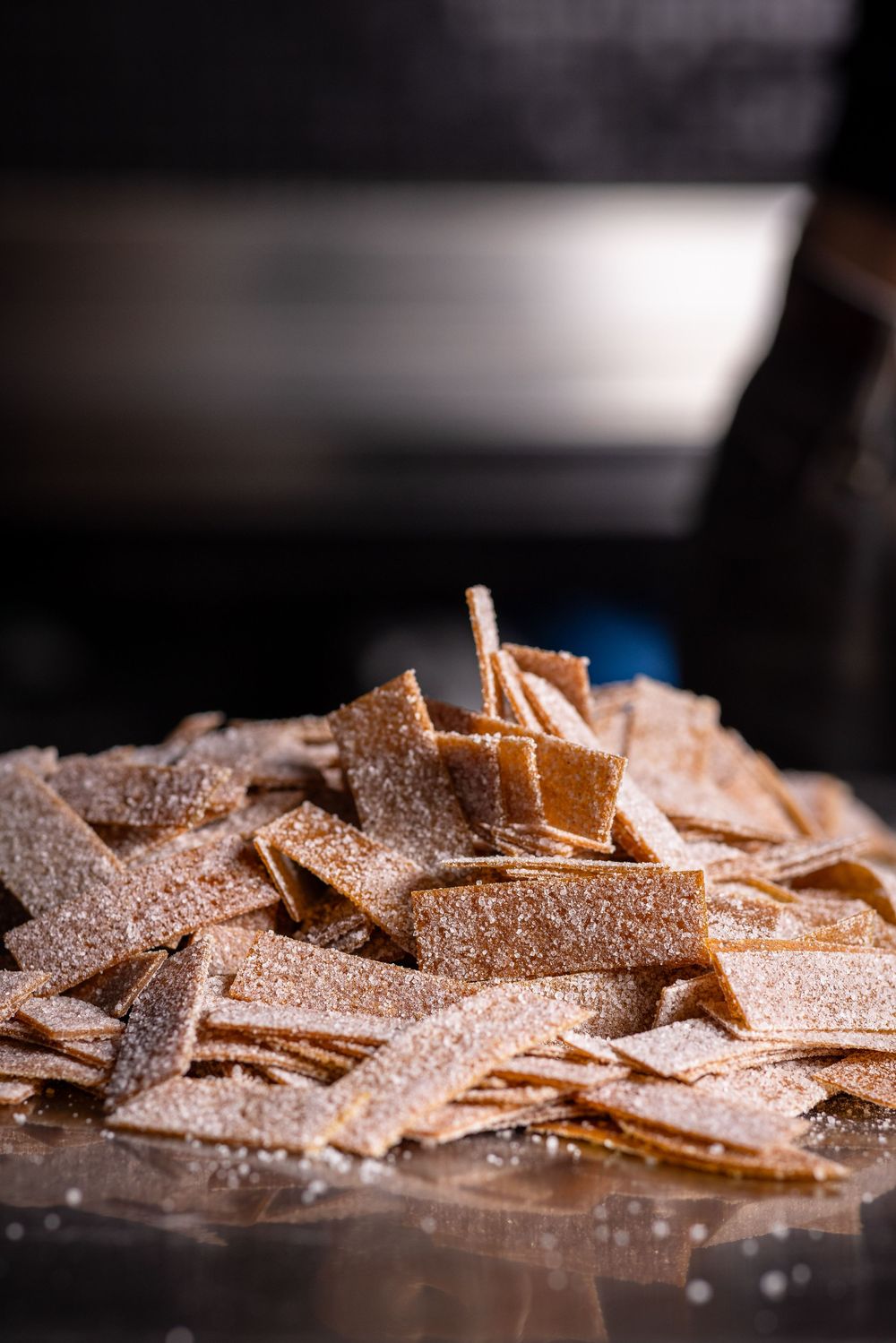 Macro shot of chocolate shavings and curls with powdered sugar dusting on dark background.