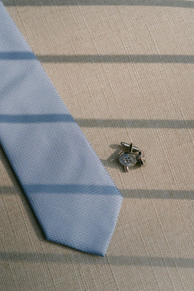 Light blue necktie laid flat on a beige textured surface.