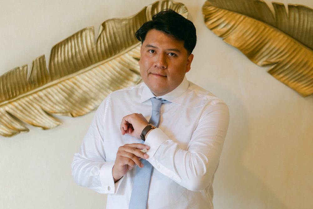 A sequence of photos showing someone in a white dress shirt adjusting their tie against a beige wall.