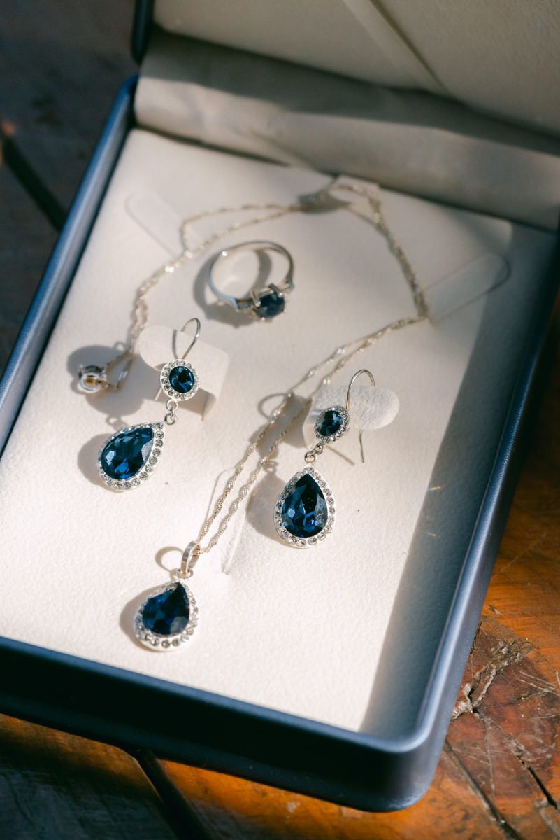 Elegant blue gemstone jewelry set with matching necklace and earrings displayed on white cards in a dark box.