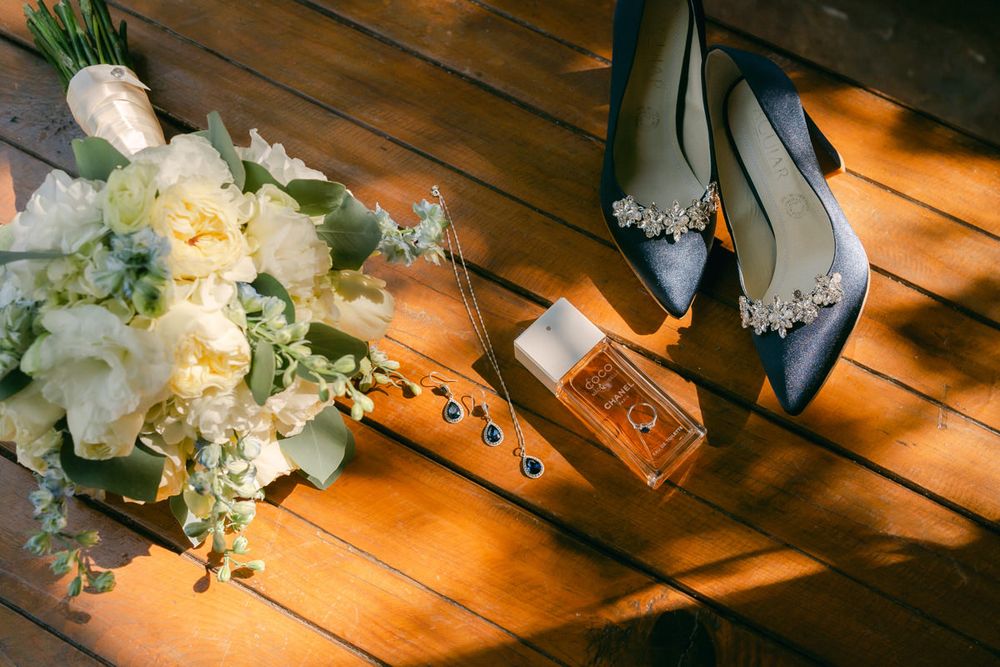 Wedding bouquet and decorative items arranged on a rustic wooden table with warm lighting.