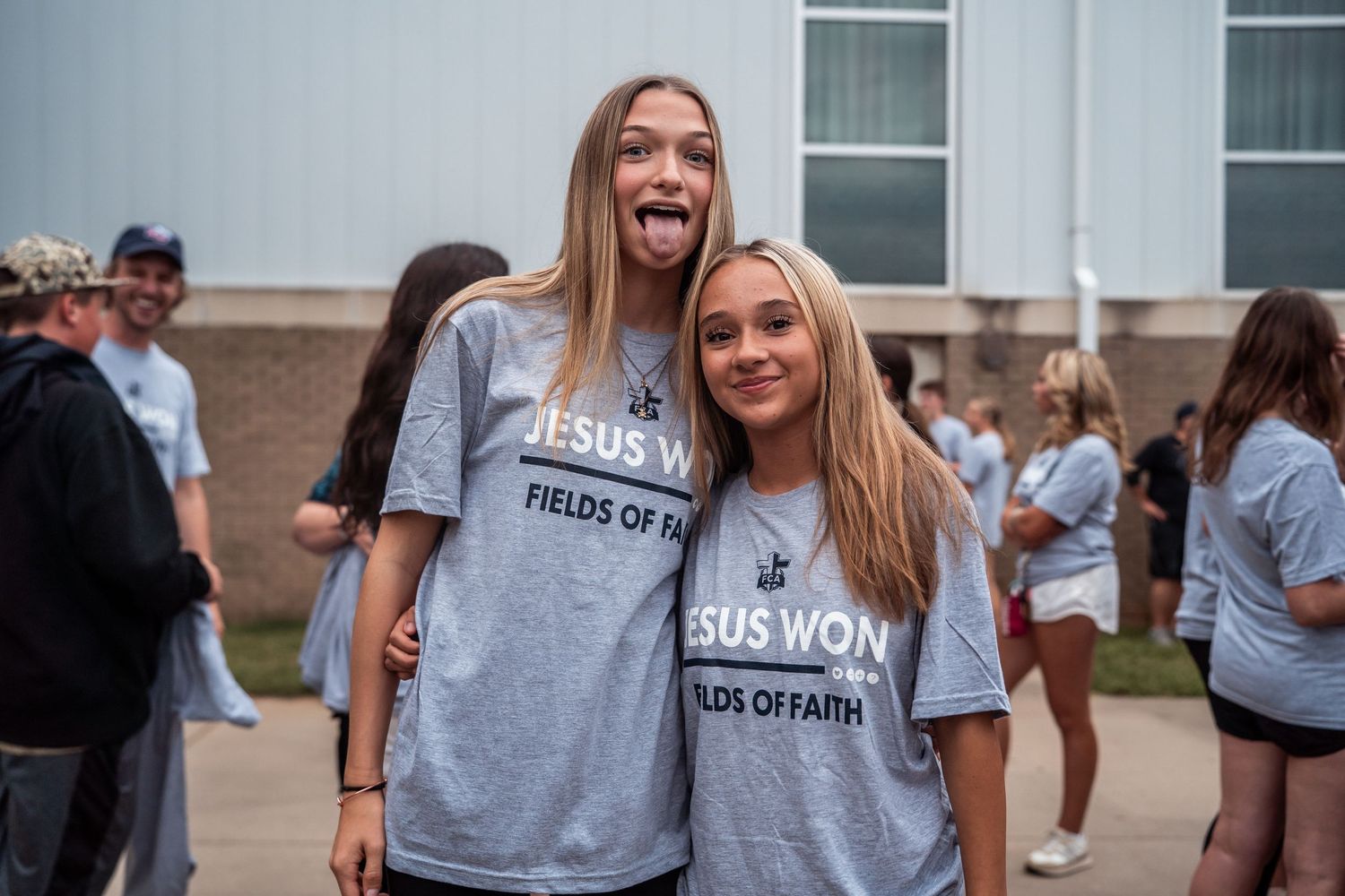Students wearing matching gray t-shirts smile and pose together during a school event or gathering.