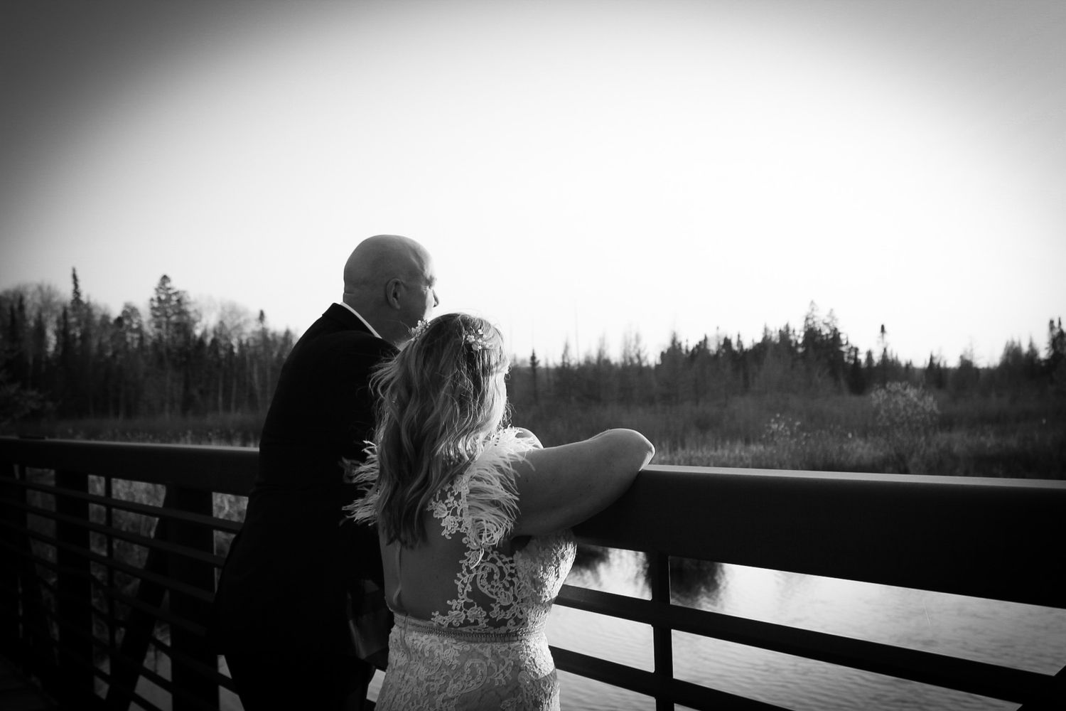Silhouetted couple shares a romantic moment against a misty outdoor backdrop with trees and a fence.