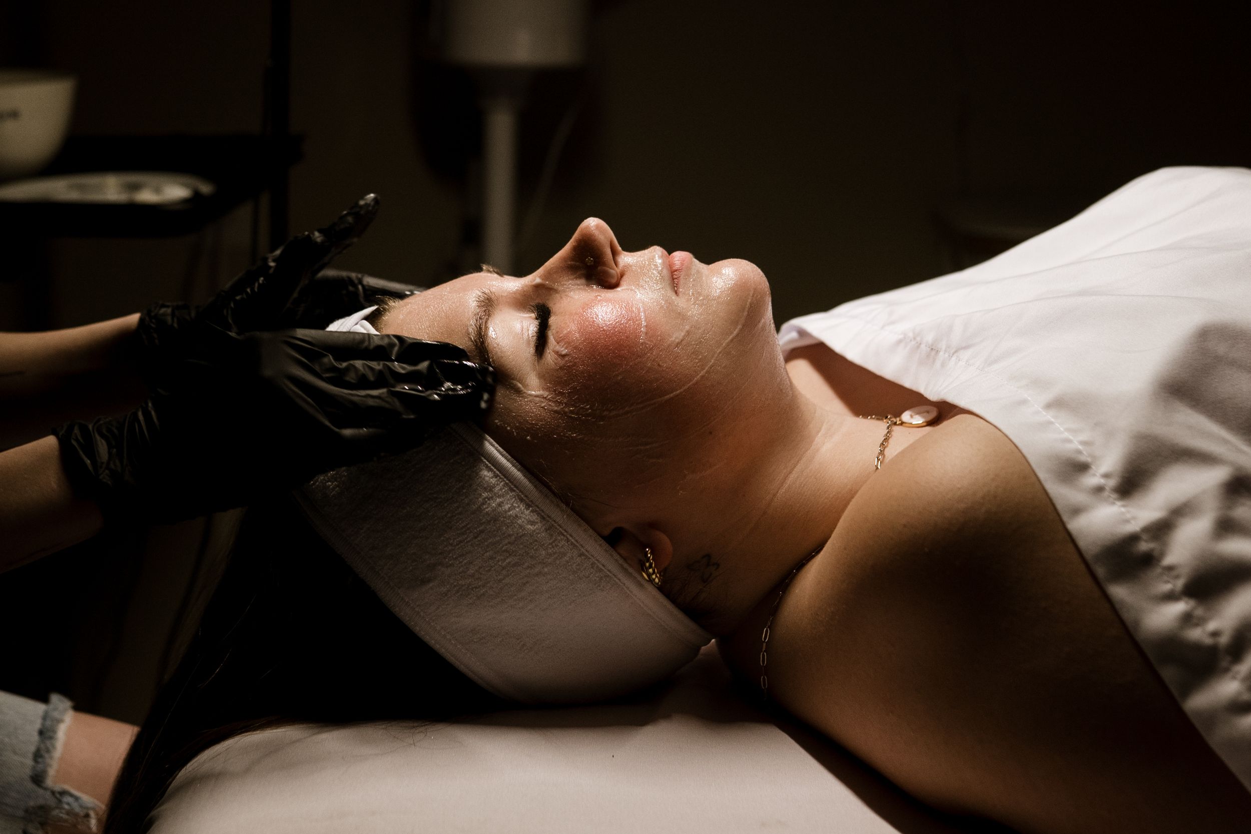 A person lies on white bedding while sleeping peacefully in a dark room.
