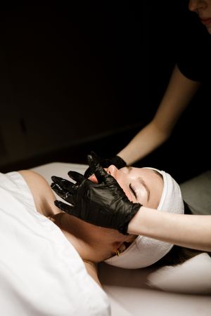 A pair of hands performing a relaxing massage therapy treatment on a white massage table surface.