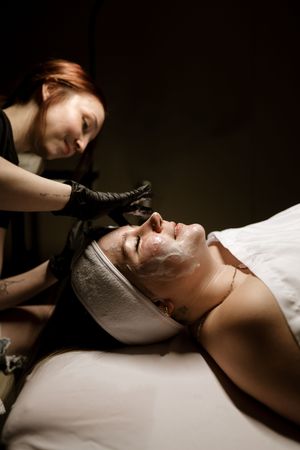 Dramatic spa treatment sequence showing facial mask application in dark moody lighting.