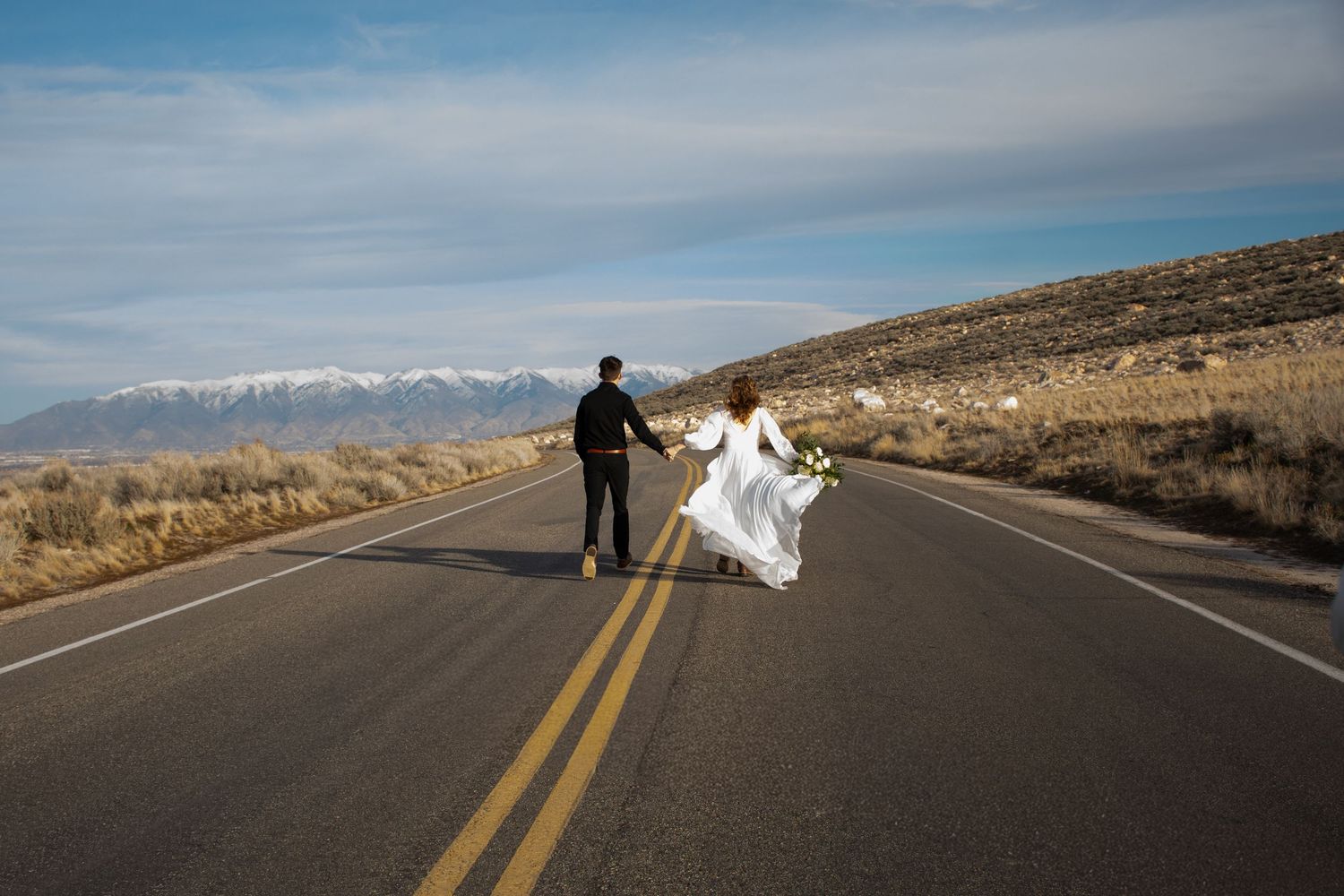 A series of wedding dress photos taken on an empty desert highway with mountains in the background.