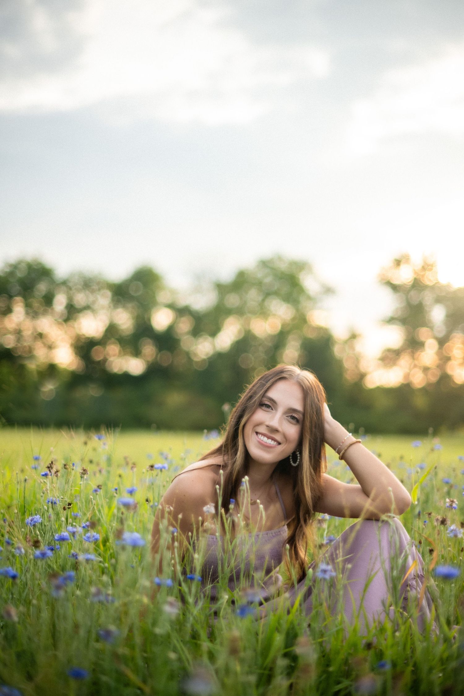 A series of outdoor portrait photos showing someone with curly hair posing in a field of wildflowers at sunset.