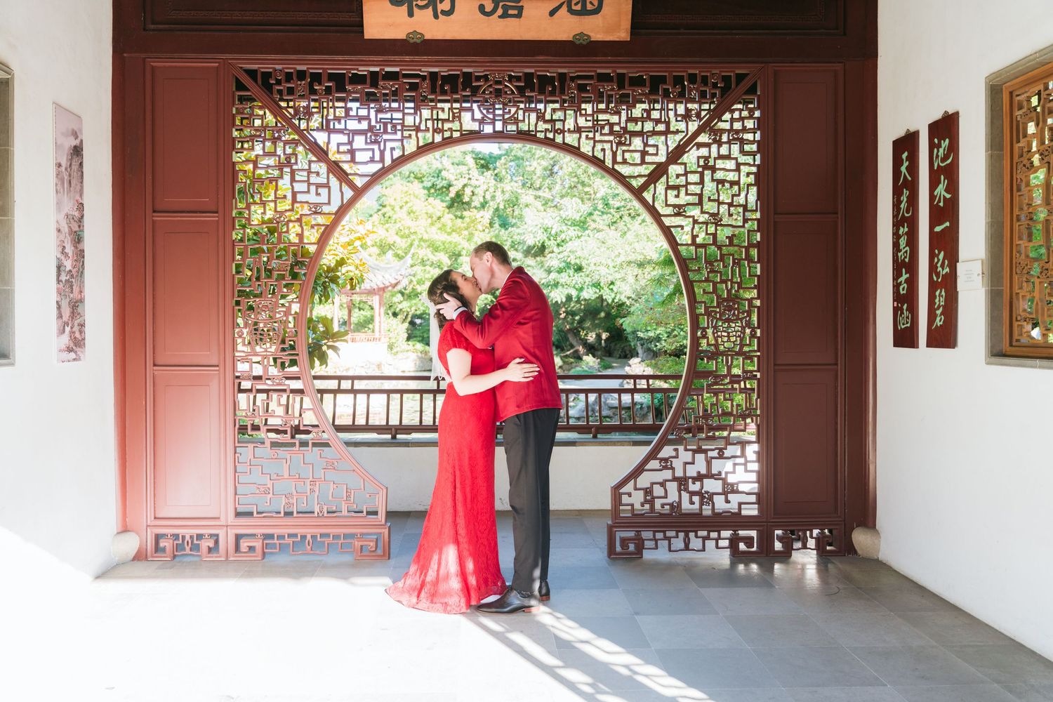 A panoramic view of a traditional Chinese garden walkway with ornate lattice windows and red architectural details.