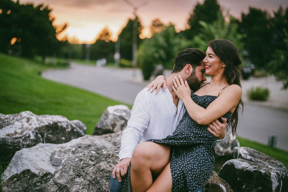 Couple shares intimate moment while sitting on rocky outcrop during golden hour.