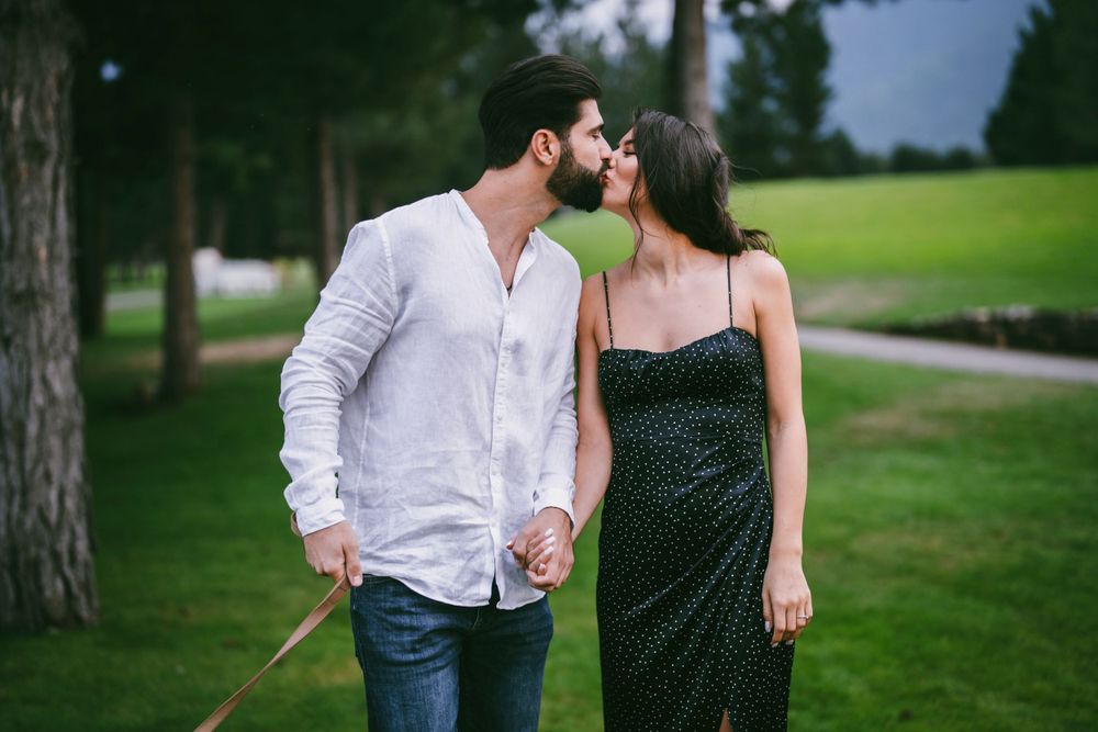 Romantic couple in elegant attire sharing an intimate moment in a park setting.