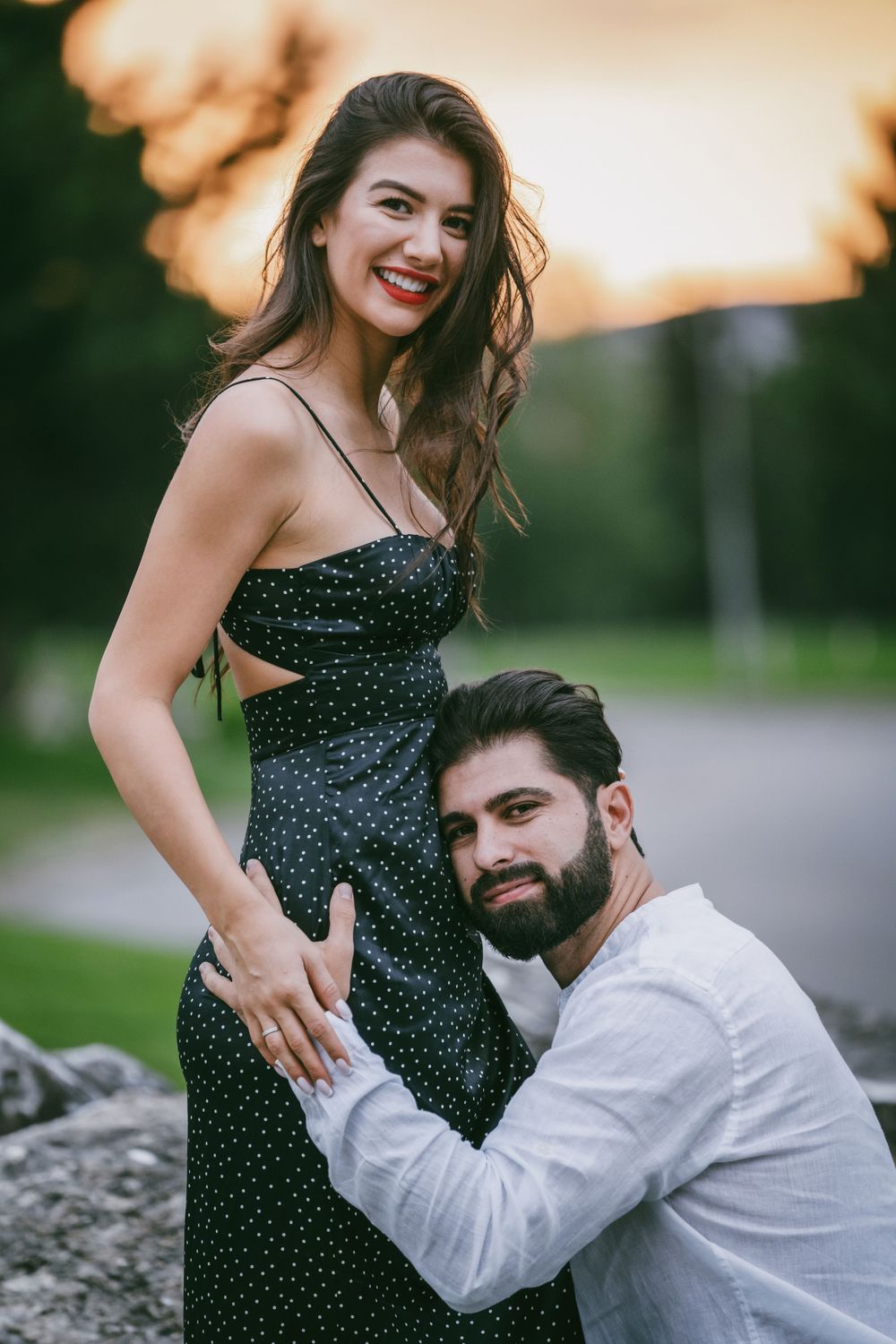 Couple poses playfully on rocks during sunset engagement session.