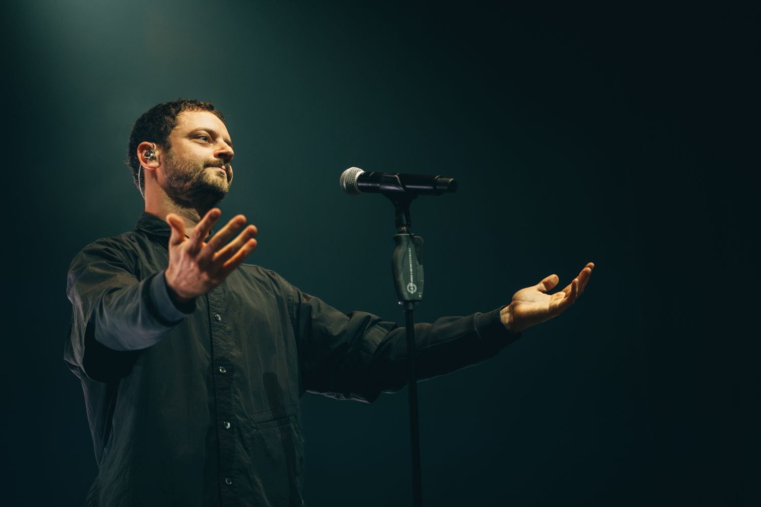 A performer sings passionately on stage with dramatic lighting and gestures during an emotional musical performance.