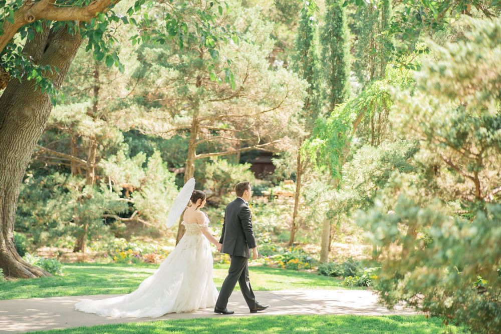 Bride and groom walking through a lush green garden on their wedding day.