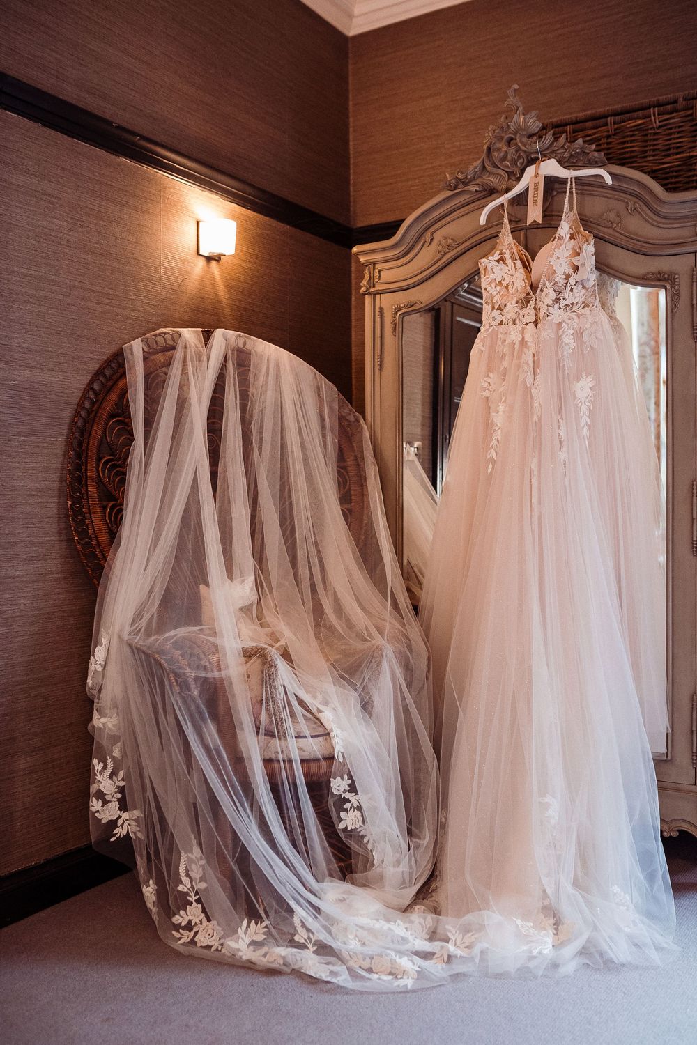 A series of ethereal white wedding dresses displayed in a dimly lit room with elegant lighting and wooden paneled walls.