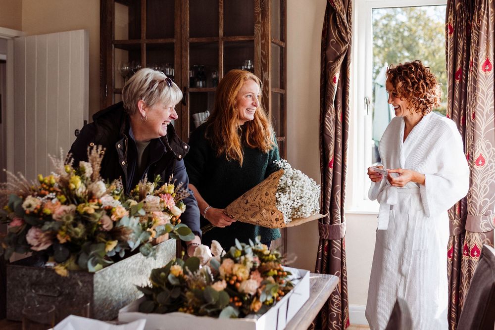 A series of candid moments captured at a wedding venue showing people in white attire and floral decorations.