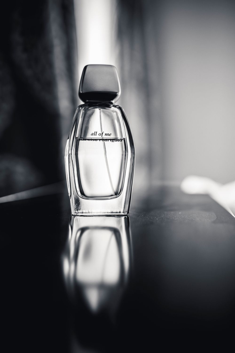 A series of artistic black and white photographs showing a perfume bottle from different angles with dramatic lighting.