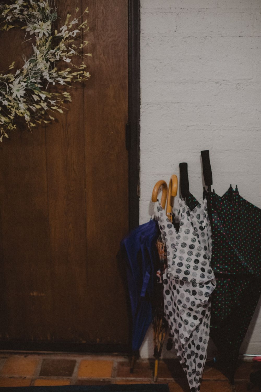 Patterned clothing hangs against a brown door and white wall creating a vintage aesthetic.