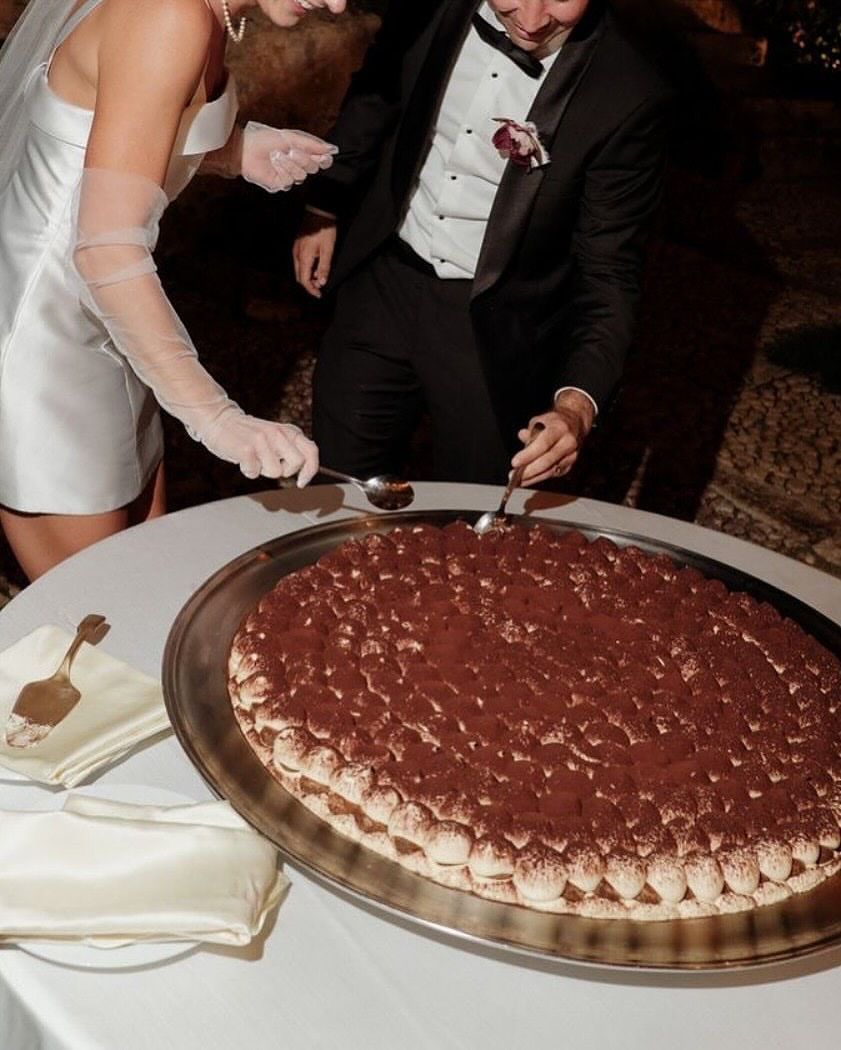 Bride and groom cutting a large tiramisu wedding cake at a reception table.