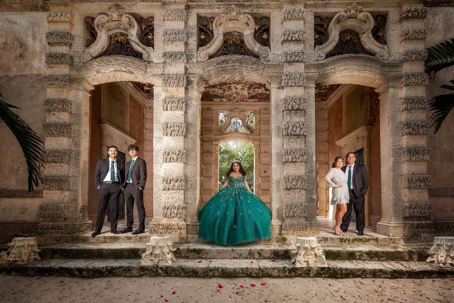 Wedding party poses in a series of stone archways at a historic venue during a formal photo session.
